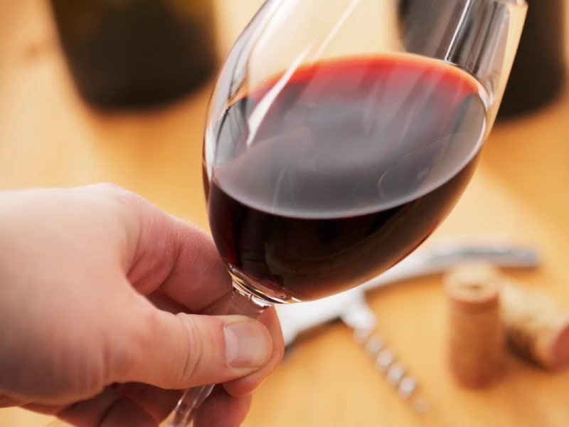 Red Wine in a glass being held and examined closeup