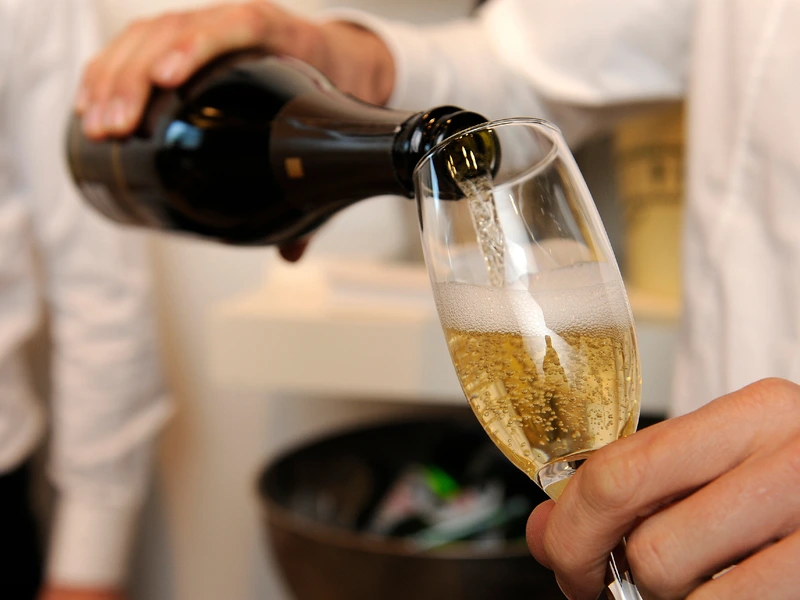 Sparkling wine poured into a glass by waiter closeup
